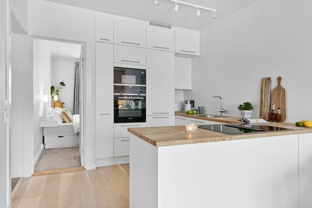 A kitchen with white cabinets and a wooden counter top